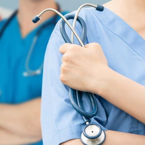 Schulterausschnitt einer medizinischen Pflegekraft mit Stethoskop in der Hand